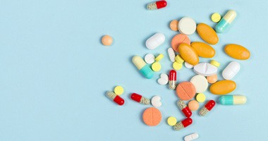 Różne tabletki farmaceutyczne, tabletki i kapsułki na niebieskim tle