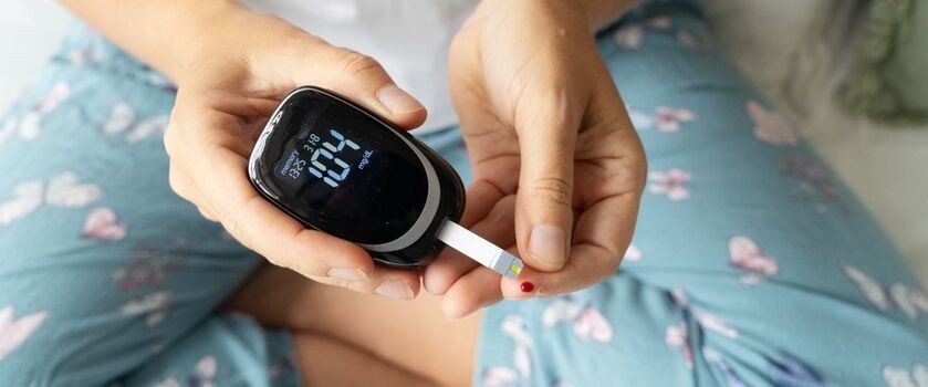 stan przedcukrzycowy, kobieta bada poziom cukru glukometrem, badanie poziomu cukru we krwi