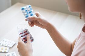 Kobieta przegląda blistry z lekami w poszukiwaniu przeterminowanych leków. Co zrobić z przeterminowanymi lekami, gdzie wyrzucić blistry po lekach?