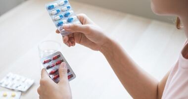 Kobieta przegląda blistry z lekami w poszukiwaniu przeterminowanych leków. Co zrobić z przeterminowanymi lekami, gdzie wyrzucić blistry po lekach?