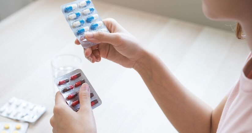 Kobieta przegląda blistry z lekami w poszukiwaniu przeterminowanych leków. Co zrobić z przeterminowanymi lekami, gdzie wyrzucić blistry po lekach?