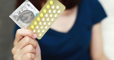 Prezerwatywa i pigułki antykoncepcyjne w kobiecej dłoni. Jaka antykoncepcja po porodzie?