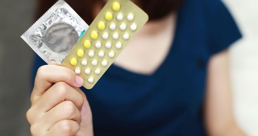Prezerwatywa i pigułki antykoncepcyjne w kobiecej dłoni. Jaka antykoncepcja po porodzie?