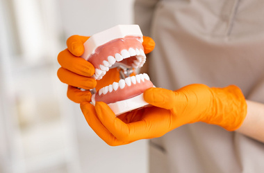dentysta trzymający protezę zębowa, jak dbać o protezę zębową