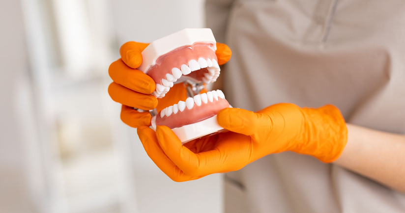 dentysta trzymający protezę zębowa, jak dbać o protezę zębową