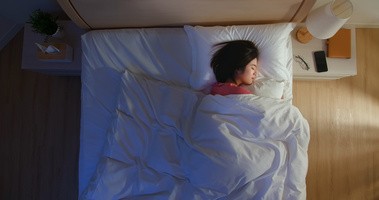 Osoba śpi w łóżku cierpiąc na płytki sen