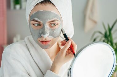 domowe sposoby an trądzik, domowe maseczki, maska z glinki na trądzik, kobieta nakłada maseczkę z glinki