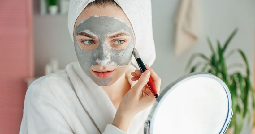 domowe sposoby an trądzik, domowe maseczki, maska z glinki na trądzik, kobieta nakłada maseczkę z glinki