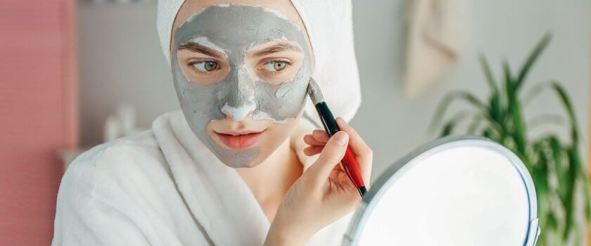 domowe sposoby an trądzik, domowe maseczki, maska z glinki na trądzik, kobieta nakłada maseczkę z glinki