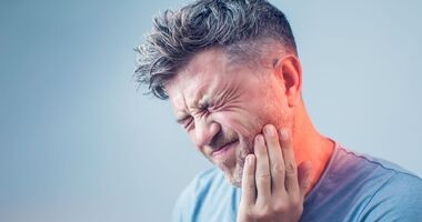 Mężczyzna trzyma się za bolącą twarz, czując ból zęba