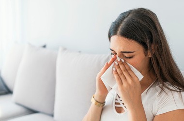 Kobieta dmuchająca nos z objawami alergicznymi