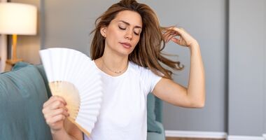 przedwczesna menopauza, wczesna menopauza, kobieta z uderzaniami gorąca wachluje się