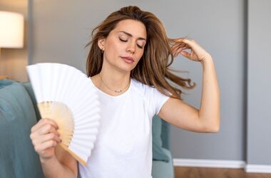 przedwczesna menopauza, wczesna menopauza, kobieta z uderzaniami gorąca wachluje się