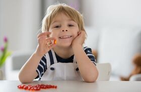 dziecko z witaminą w ręku, suplementy i witaminy na odporność, jak uniknąć infekcji