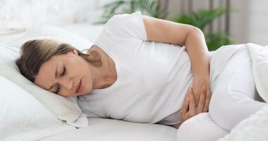endometrioza, dieta przy endometriozie, kobieta z bólem podbrzusza na łóżku