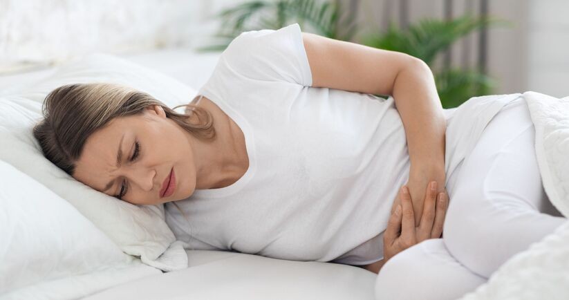 endometrioza, dieta przy endometriozie, kobieta z bólem podbrzusza na łóżku
