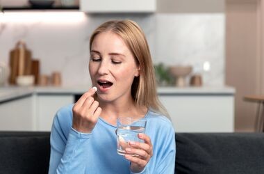 Kobieta trzyma szklankę z wodą i tabletkę aspiryny, jak działa aspiryna