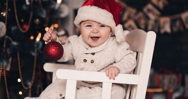 Dziecko w foteliku przy choince. Potrawy wigilijne dla dzieci i niemowląt, co może jeść w wigilię niemowlę, niemowlę na wigilii.