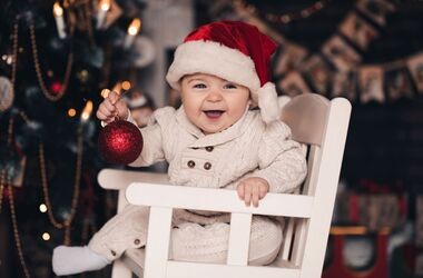 Dziecko w foteliku przy choince. Potrawy wigilijne dla dzieci i niemowląt, co może jeść w wigilię niemowlę, niemowlę na wigilii.