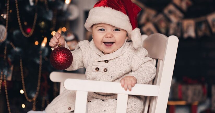 Dziecko w foteliku przy choince. Potrawy wigilijne dla dzieci i niemowląt, co może jeść w wigilię niemowlę, niemowlę na wigilii.