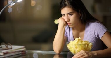 Smutna kobieta z miską czipsów. Jak nie przytyć po rzuceniu palenia?