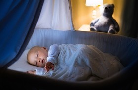 Dziecko zasypia w kołysce w zaciemnionym pokoju