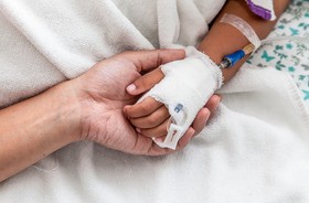 Ręka matki trzyma rękę dziecka chorującego na PIMS-TS