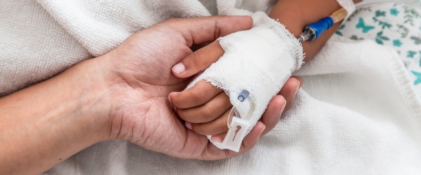 Ręka matki trzyma rękę dziecka chorującego na PIMS-TS