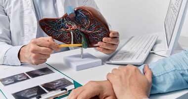 WZW, wirusowe zapalenie wątroby, objawy wirusowego zapalenia wątroby, rodzaje wirusowego zapalenia wątroby, wiruswe zapalenie wątroby typu, lekarz pokazuje pacjentowi model wątroby