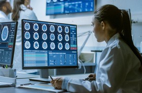 Kobieta naukowiec zajmująca się badaniami medycznymi, pracująca ze skanami mózgu widcznymi na komputerze