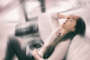 Kobieta z zawrotami głowy leży na kanapie