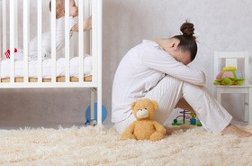 Kobieta w depresji poporodowej przy łóżeczku swojego dziecka