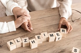 Starszy pacjent układa z klocków napis Alzheimer