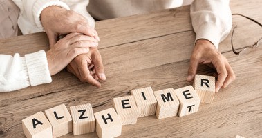 Starszy pacjent układa z klocków napis Alzheimer