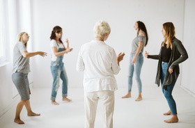 Grupka kobiet uprawia w kółeczku terapię tańcem