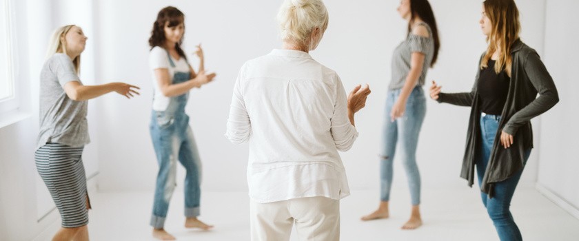 Grupka kobiet uprawia w kółeczku terapię tańcem