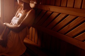 Kobieta w ręczniku siedzi w saunie