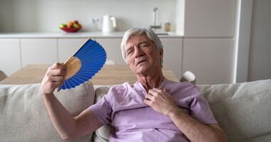 upał, choroby serca a upał, starszy mężczyzna wachluje się na kanapie