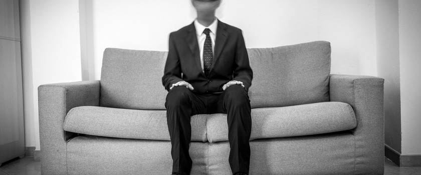 Mężczyzna na kanapie z rozmytą głową - alegoria zespołu depersonalizacji-derealizacji (DD)