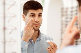 soczewki przy astygmatyzmie, soczewki toryczne, mężczyzna przymierza soczewki w salonie optycznym