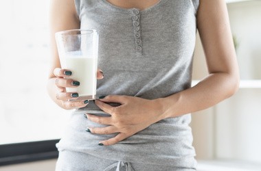 Kobieta ze szklanką mleka, cierpiąca na nietolerancję laktozy.