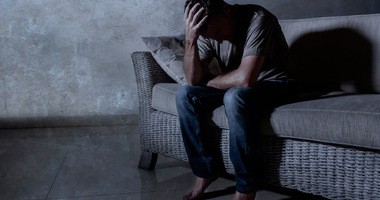 Mężczyzna w depresji siedzi zrozpaczony na skraju łóżka