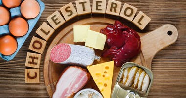 Niedrowe, tłuste produkty, które podwyższaja poziom cholesterolu, leżą na drewnianytm stole.