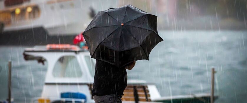 człowiek z parasolem idzie w deszczu