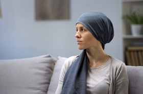 Pacjentka podczas terapii onkologicznej siedzi na kanapie, majac smutny wyraz twarzy