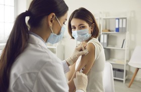 Młoda kobieta w masce na twarz dostaje w szpitalu szczepionkę przeciwko koronawirusowi