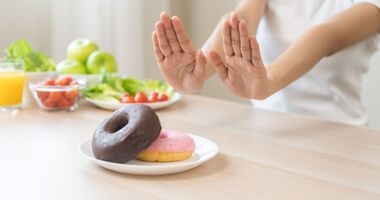 Dłonie odsuwające talerz z pączkami. Dieta odchudzająca, dieta na odchudzanie.