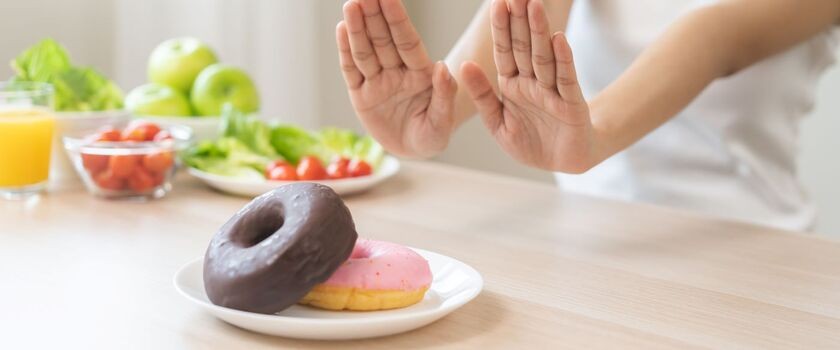Dłonie odsuwające talerz z pączkami. Dieta odchudzająca, dieta na odchudzanie.