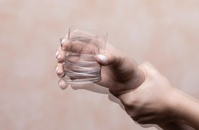 Drżąca, trzęsąca się ręka unosi szklankę z wodą
