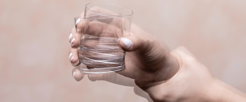 Drżąca, trzęsąca się ręka unosi szklankę z wodą